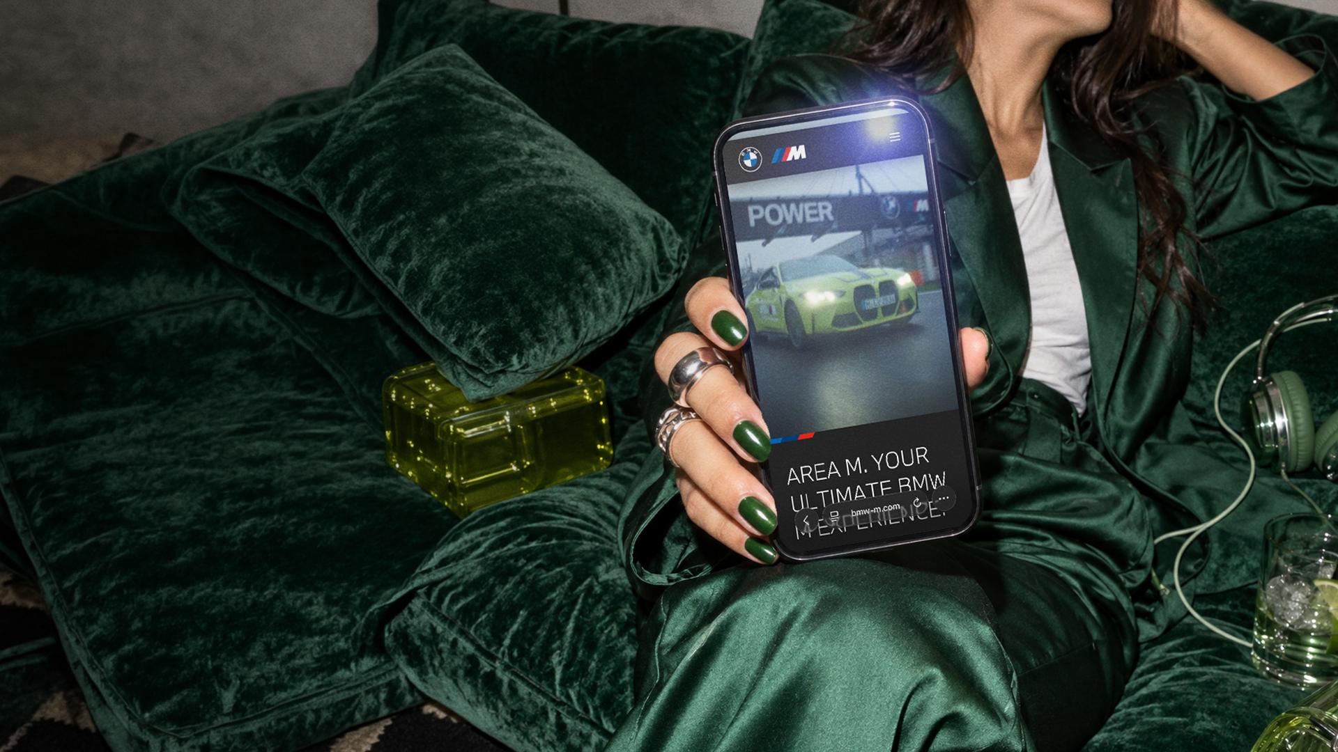 Person holding a smartphone displaying a BMW M digital experience