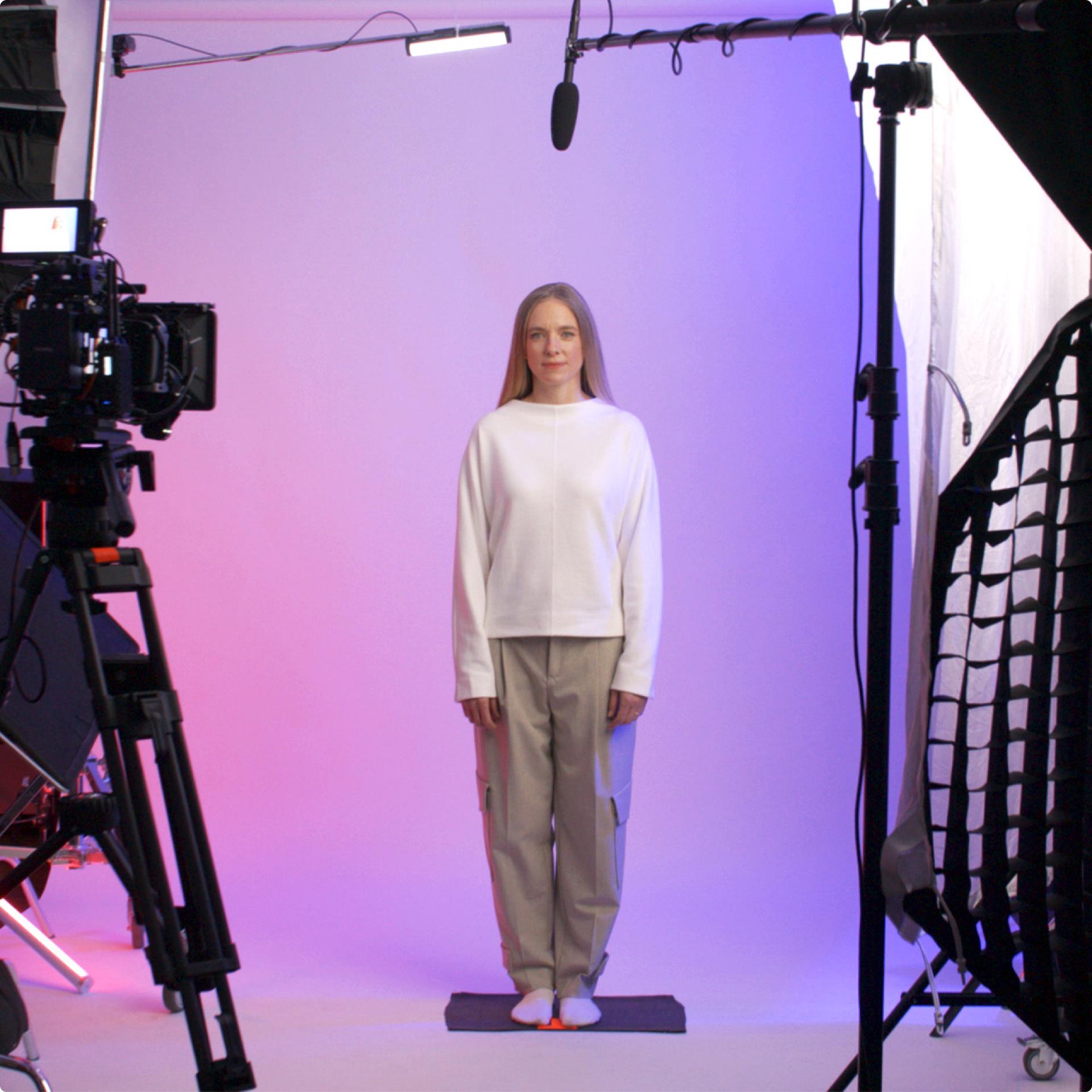 L-Bank Human Avatar standing on a studio set between a camera and lighting equipment